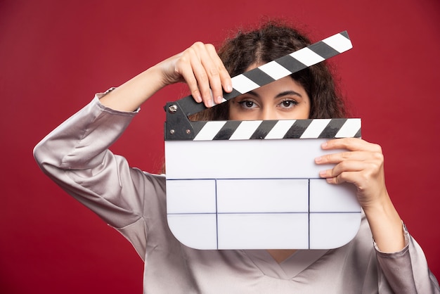 Brunette woman looking behind clapperboard.