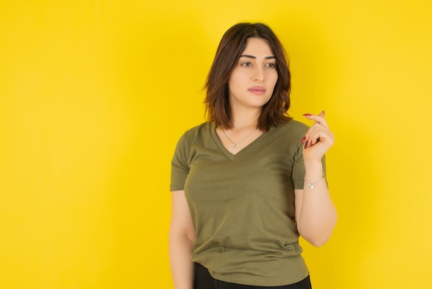 Brunette woman model standing and posing against yellow wall 