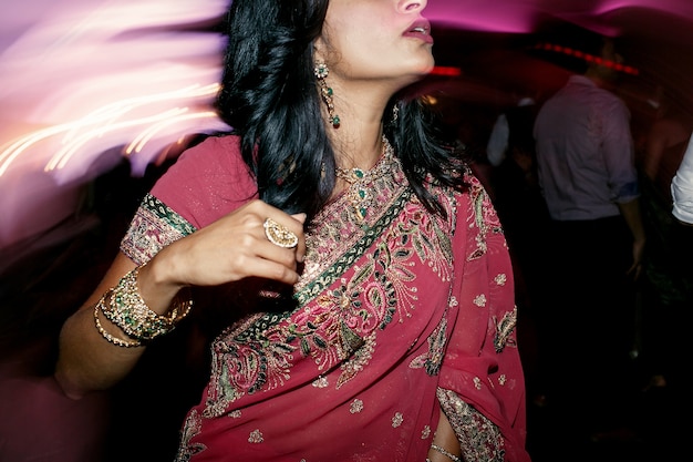 Brunette woman in pink saree stands in the crowd of people