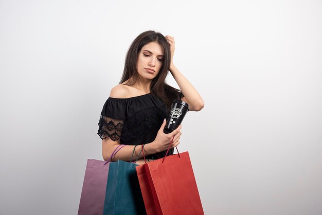 Brunette woman posing with shopping bags and coffee cup.