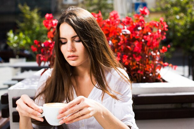 Brunette woman sits at the table with coffee