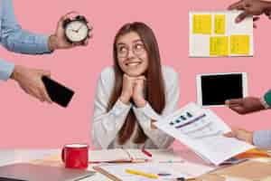 Free photo brunette woman sitting at desk surrounded with gadgets and papers