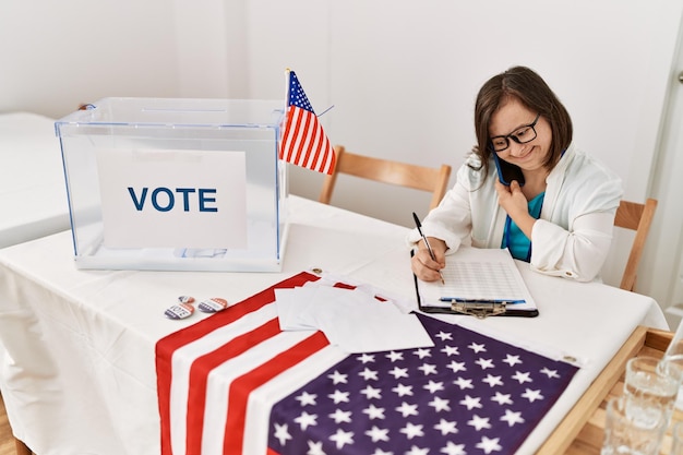 Free photo brunette woman with down syndrome writing on clipboard speaking on the phone at election room