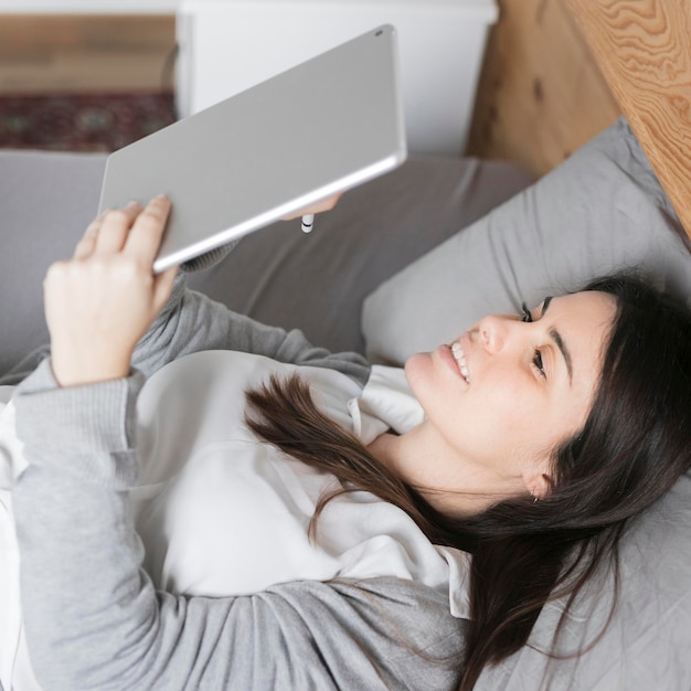 Brunette woman working on tablet in bed