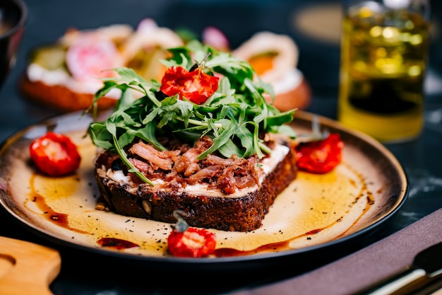 Free photo bruschetta with meat tomato arugula cream cheese sauce side view