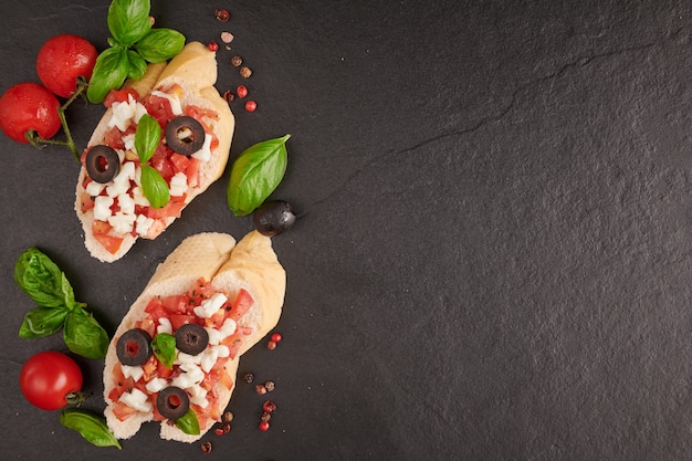 Bruschetta with tomatoes, mozzarella cheese and basil on a cutting board. Traditional italian appetizer or snack, antipasto. Caprese salad bruschetta. Top view with copy space. Flat lay.