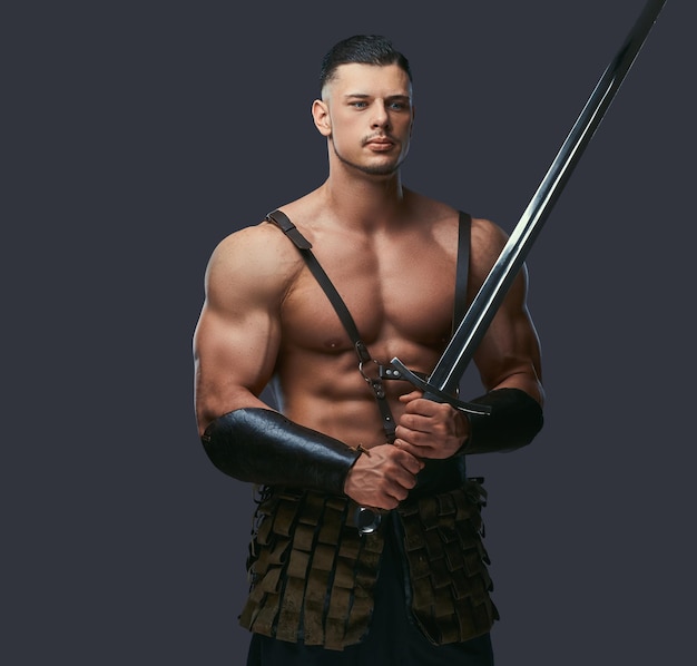 Free Photo brutal ancient greece warrior with a muscular body in battle uniforms posing on a dark background.