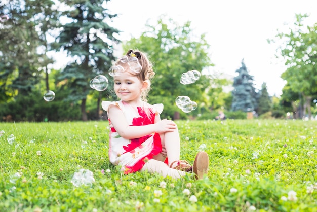 Free photo bubbles over the girl sitting in the park