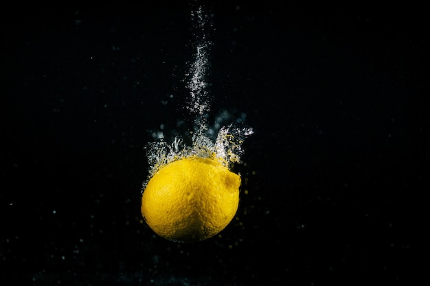 Free photo bubbles raise around yellow lemon falling in water