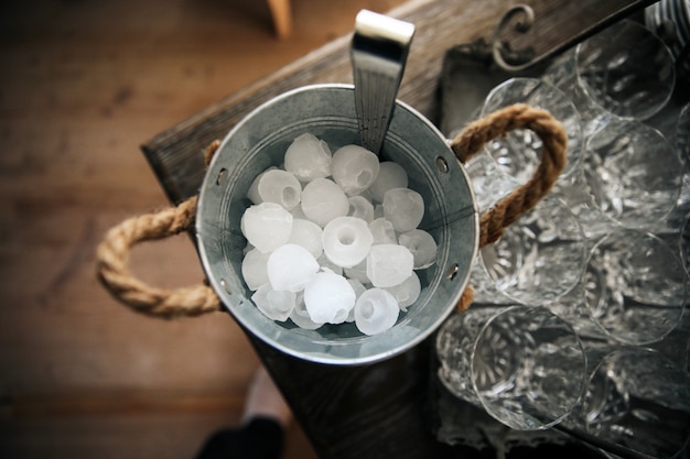 Bucket with ice stands on the table near the glasses