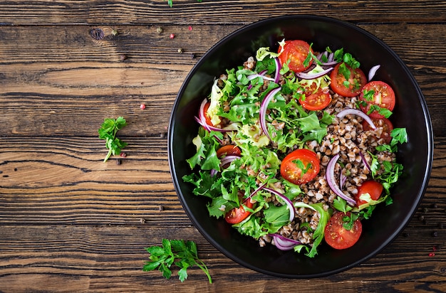 Buckwheat salad with cherry tomatoes, red onion and fresh herbs. Vegan food. Diet menu. Top view. Flat lay