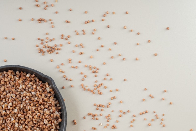 Buckwheat seeds in a dish on concrete.