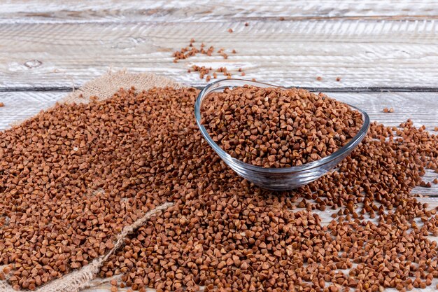 Buckwheats in a bowl and alongside. high angle view on a light wooden 