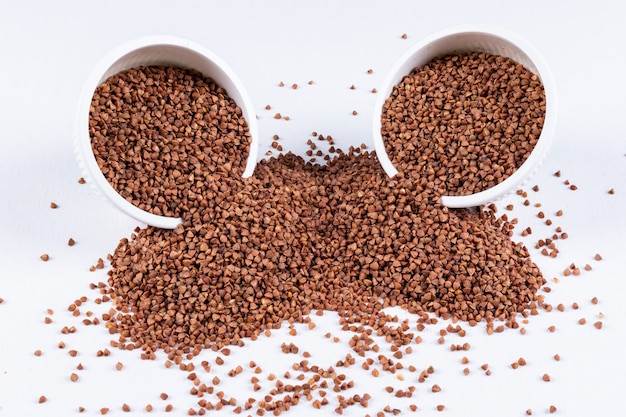 Buckwheats in a bowls and around high angle view on a white 