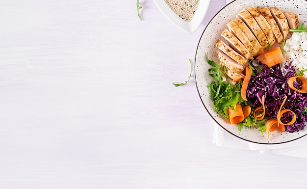 Free photo buddha bowl dish with chicken fillet, rice,  red cabbage, carrot, fresh lettuce salad and sesame.