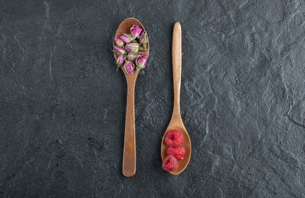 Free photo budding roses and raspberries on wooden spoons.