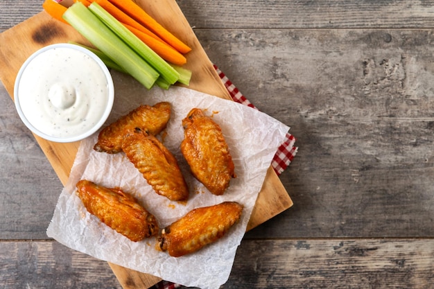 Free photo buffalo spicy chicken wings with cayenne pepper sauce on wooden table