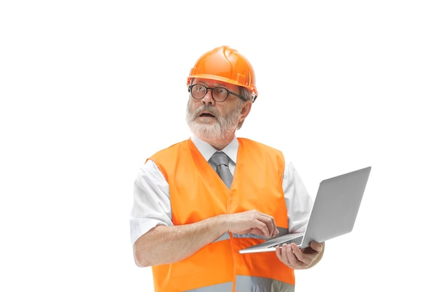 builder in a construction vest and an orange helmet with laptop.