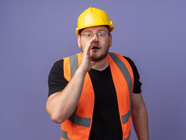 Builder man in construction vest and safety helmetwhispering a secret with hand near mouth