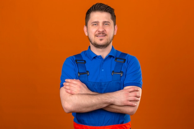 Free Photo builder man wearing construction uniform standing with arms crossed with confident smile over isolated orange wall