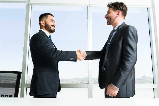 Building collaborative teamwork. Handsome businessman and business executive getting to know each other while shaking hands during a work meeting