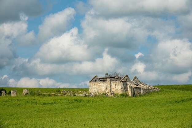 Building constructed on a green field under a sky full of clouds during daytime