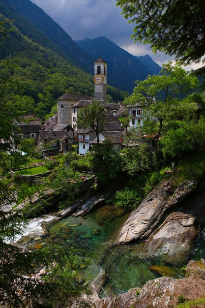 Buildings near river, trees, and rocks during day