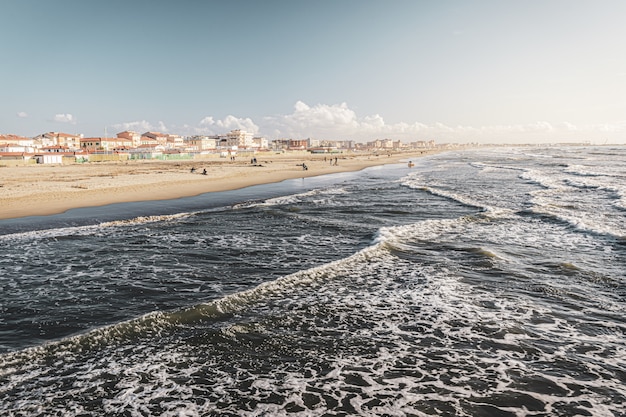 buildings on the shore near crazy sea waves