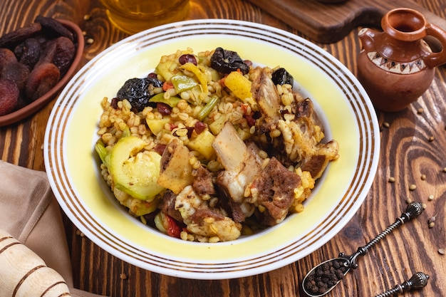 Bulgur with meat zucchini prunes beans bell pepper dry fruits side view