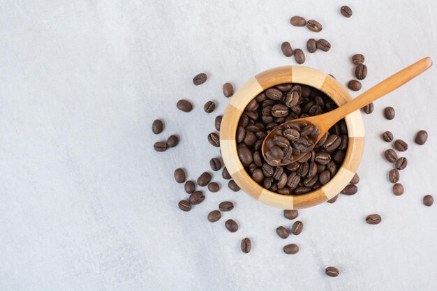 Bunch of coffee beans in wooden bowl with spoon