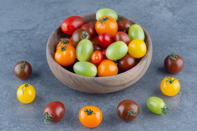 Bunch of colorful tomatoes in wooden bowl.