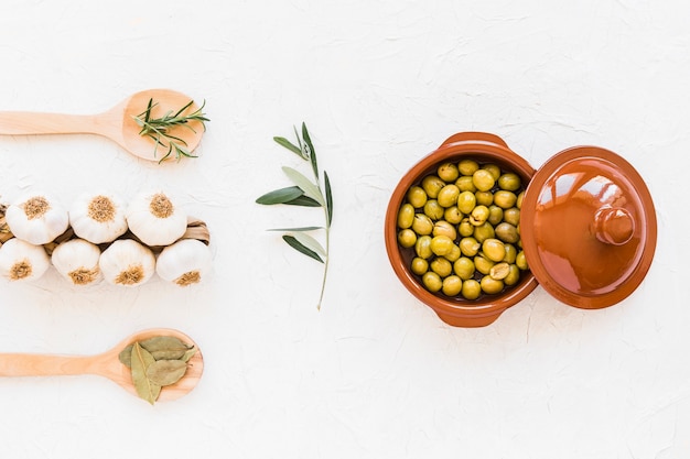 Bunch of garlic bulbs with herbs and fresh green olives