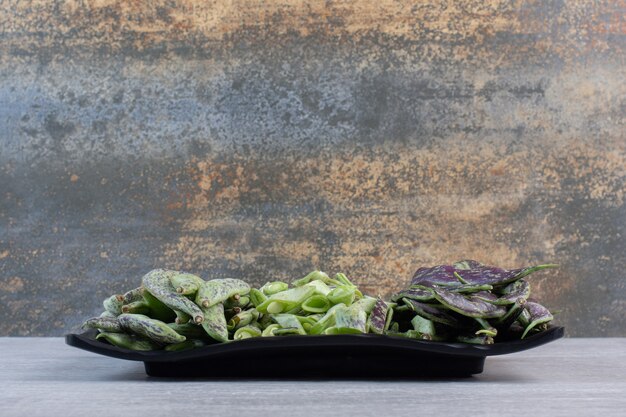 Bunch of green beans placed on black plate. High quality photo