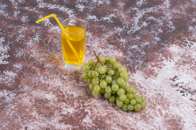 Free photo a bunch of green grapes and a glass of juice