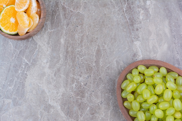 Bunch of green grapes in wooden bowl and citrus fruits. 