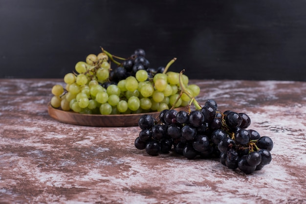 A bunch of green and red grapes in a wooden platter