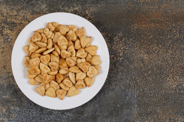 Bunch of heart shaped crackers on white plate.