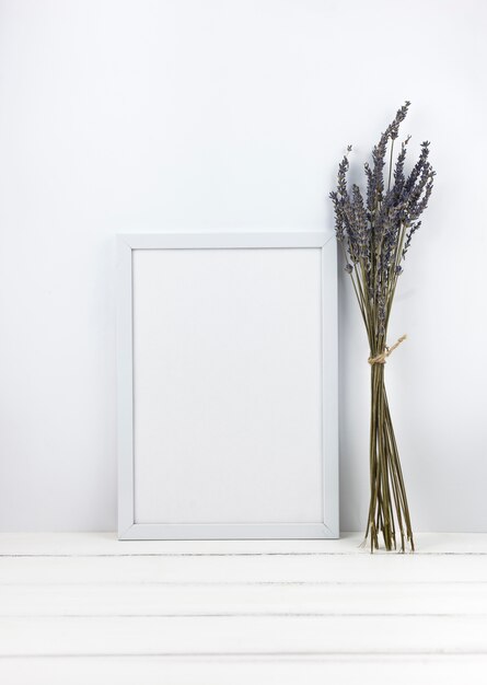 Bunch of lavender flowers with empty frame on wooden desk