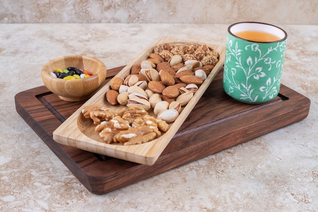 Free photo bunch of nut kernels on wooden plate with hot tea