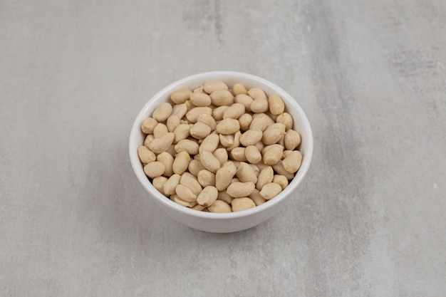 Bunch of peeled peanuts in white bowl.