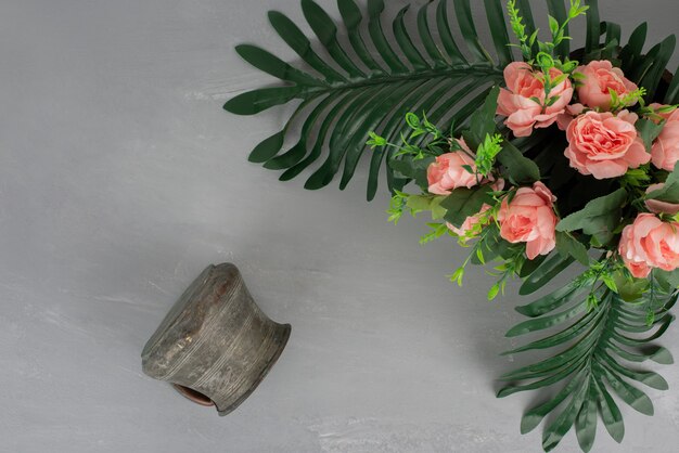 Bunch of pink roses with leaves and vase on grey surface