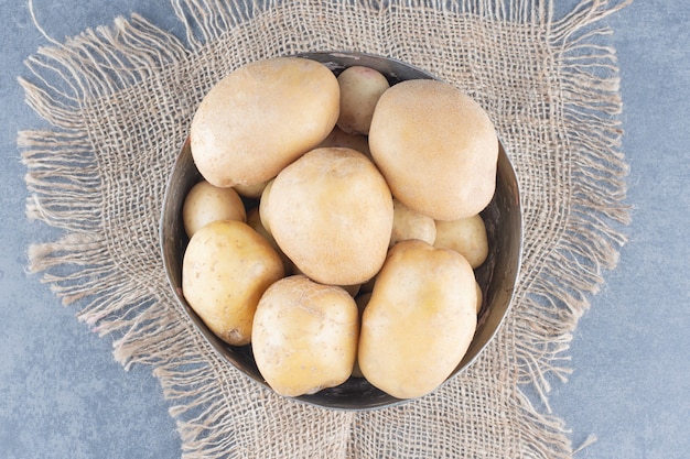 Bunch of potatoes in metal mug with burlap.