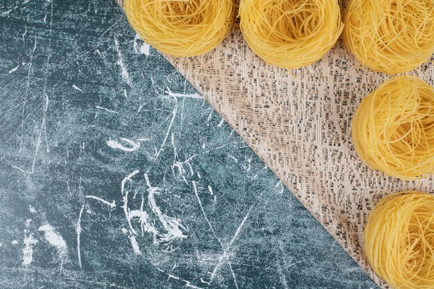 Bunch of raw spaghetti nests on burlap. High quality photo