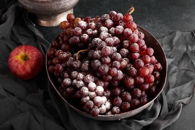 A bunch of red grapes in a metallic bowl, top view. 