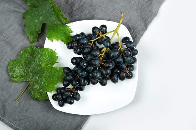 A bunch of red grapes in a white plate. 