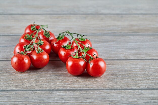 Bunch of red tomatoes with branch on wooden table