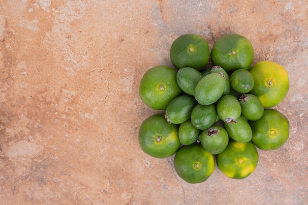 Free photo bunch of tangerines and feijoas on orange surface.