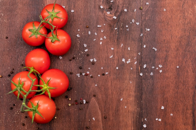 bunch of tomato on wooden texture with scattered salt