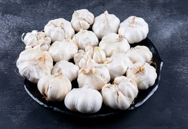 Bunches of garlic on a dark textured table.