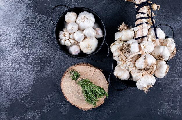 Bunches of garlic and rosemary with some of it in a bucket top view